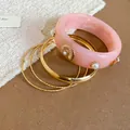 Detailed view of pink resin and gold metal bracelet set with pearl accents. - Gold, Pink