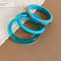 Close-up of a stylish three-piece blue resin bangle set featuring colorful rhinestones - Blue