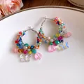 Detailed macro view of colorful beaded hoop earrings featuring iridescent butterfly charms. - Small / Colorful