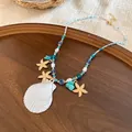 Bohemian beach style necklace with white shell pendant, pearls, and starfish charms - Gold-Blue