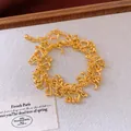 Vue détaillée d'un bracelet doré géométrique irrégulier sur un fond en tissu texturé - Bracelet / Or