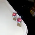 Close-up macro view of square red zircon stud earrings with sparkling halo and silver plating - Earrings / Silver-Red