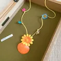 Vibrant seaside vacation necklace featuring shell and flower pendants on a yellow cord strap - Yellow-Orange
