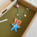 Summer beach style necklace with blue starfish and flower charms on blue cord cord - Blue-Brown