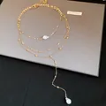 Detailed shot of a layered gold necklace featuring elegant baroque pearl pendants. - Gold