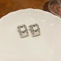 Close-up of heart pattern and zircon detailing on silver filigree earrings. - Heart Style / Silver