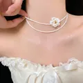 Elegant double-layer pearl choker necklace featuring a delicate white flower charm. - White