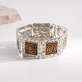 Close-up of retro silver bracelet with amber enamel spiral pattern and dot texture - Silver-Coffee