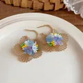 Gros plan détaillé de boucles d'oreilles fleur en filigrane doré avec perles colorées. - Or-Bleu