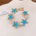 Exquisite Detailansicht eines Seestern-Armbands mit blauer Emaille und Perlen - Blau