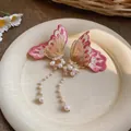 Elegant close-up detail of embroidered butterfly earrings featuring long pearl tassels - Pink
