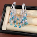 Close-up detail of luxury teardrop tassel earrings featuring blue and white zircons - 18K Gold Plated (HE34037) / Silver-Blue