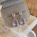 Close-up view of elegant pink teardrop zircon dangle earrings in a velvet box - Pink