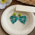 Macro detail view of teal marble swirl resin leaf earrings on a minimalist cream tray - Leaf Style (HE32524) / Green