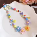 Detailed view of colorful dopamine style beaded necklace with daisy floral charms on a tray - Colorful