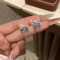 Elegant close-up of bowknot zircon stud earrings featuring blue heart-shaped stones - Bowknot Heart Cherry Style / Silver Earring Post-Blue