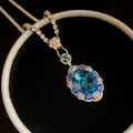 Close-up of blue oval gemstone pendant with sparkling crystal halo and silver chain - Silver-Blue