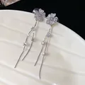 Detailed close-up of sparkling zircon flower stud earrings with elegant long tassels - Silver