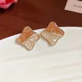 Close-up macro detail of geometric stud earrings with orange and white crushed glass stones - Geometric / Gold Brown