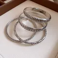 Close-up detail of a silver geometric bangle set with intricate engraved patterns. - Four-Piece Set / Silver