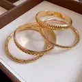 Detail view of golden geometric bangle set with textured and smooth finishes - Four-Piece Set / Gold