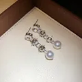 Close-up view of silver-tone drop earrings with sparkling crystals and elegant pearls. - Earrings / Silver Needle / Silver