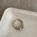Primo piano di un anello regolabile in argento vintage con zircone e dettagli intrecciati - Oro Caffè Chiaro
