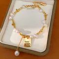 Vista dettagliata di un braccialetto di perle placcato oro 18K con ciondolo Good Luck - Stile Etichetta Good Luck Perla d'Acqua Dolce (HB6054) / Oro Con Beige (Placcato Oro)