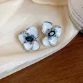 Close-up detail of vintage flower stud earrings with white enamel and blue crystals on silk - Silver Earring Post - Silver - Blue