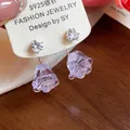 Detailansicht der herzförmigen Zirkonia-Ohrstecker mit lila Harzblumenanhänger - Silbernadel-Silber-Lila