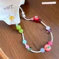 Detailed view of handmade beaded necklace with pearls and colorful apple charms - White-Green-Red