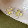 Primer plano detallado de elegantes pendientes de flor estilo francés con perlas y esmalte - Amarillo