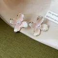 Vista detallada de elegantes pendientes de flor con pétalos de esmalte rosa y una perla - Rosa