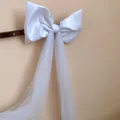 Detailed view of a white fabric bow hair clip with long elegant mesh tassels hanging down - White