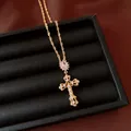 Detail van sierlijke 18k vergulde zirkoon kruis hanger in een zwarte geschenkdoos. - Ketting / Goud