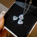 Macro view of zircon heart jewelry set featuring blue stones and sparkling crystals. - Necklace & Earrings (2-Piece Ensemble) / Silver-Blue