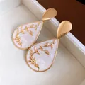 Close-up of vintage gold water drop earrings with white enamel and floral pattern. - Teardrop Pendant / Gold-White