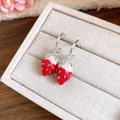 Close-up of sweet strawberry pendant earrings on a beige jewelry box - Red