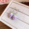 Detailed close-up of purple enamel strawberry drop earrings on a beige jewelry display tray - Purple