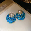Vista detallada de pendientes vintage con una perla central y piedras azules de cabujón - Azul claro