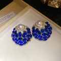 Primer plano de pendientes vintage dorados con piedras azules, cristales y perla - Azul marino