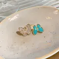 Detail view of an adjustable gold ring featuring sparkling zircon and blue resin butterflies. - Double Butterfly Open Ring / Gold (Blue Wings)