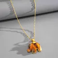 Detailed macro view of amber resin elephant pendant with sparkling eye on gold chain. - Gold Brown