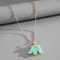 Macro view of a gold-plated necklace featuring a mint green resin elephant pendant charm - Gold-Green