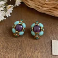 Primo piano di orecchini vintage a fiori con pietre turchesi e viola su superficie legno - Stile a Clip (Coppia) / Oro-Blu-Viola