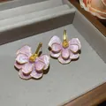 Detail view of elegant pink oil-dripped flower stud earrings in a jewelry tray. - Pink