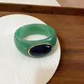 Macro view of a green acrylic marbled bangle with a navy blue oval inset. - Light Green/Dark Blue