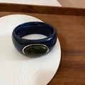 Detail of a chunky navy marbled acrylic bangle with green stone and gold frame - Blue/Dark Green