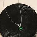 Dettaglio macro di una collana in argento con gemma verde rotonda e chiusura a V. - Ciondolo Tondo a Forma di V Verde / Argento