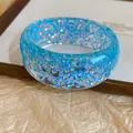 Close-up of blue resin bangle with iridescent holographic flakes and smooth finish - Blue